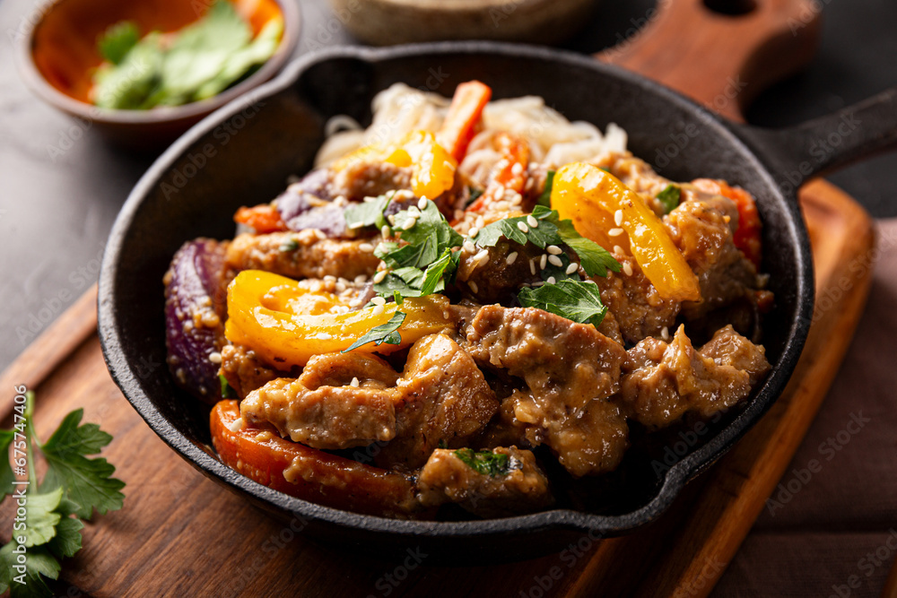 Asian pork with vegetables and glass noodles in a pan on the table