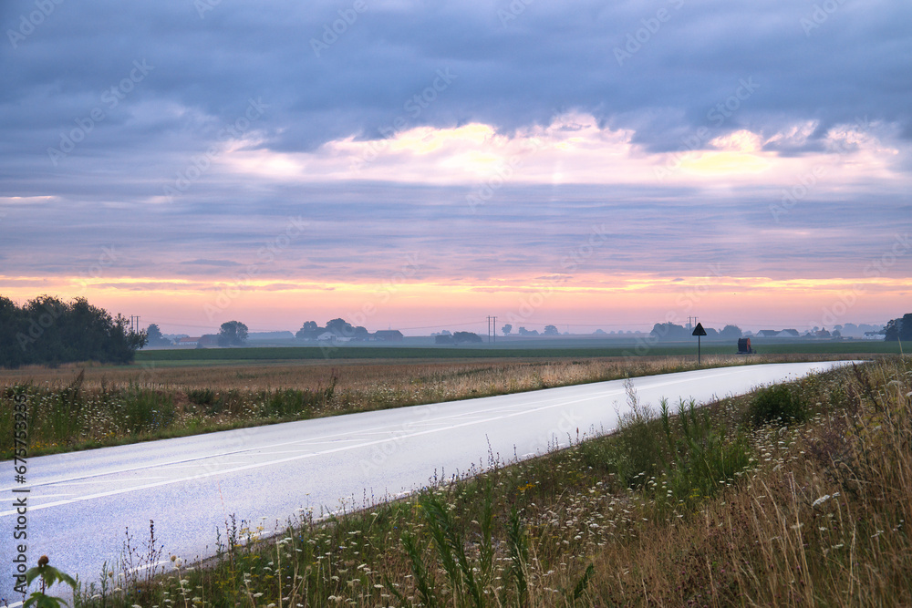 Country road with curve leads through agricultural fields. Heavy clouds in the sky Country road with curve leads through agricultural fields. Heavy clouds in the sky