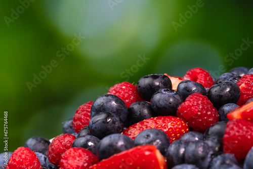Close-up of juicy blueberries  strawberries  raspberries on a green blurred background. Colorful background of berries  summer food.