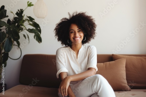 Smiling woman sitting on sofa at home. Single girl in modern living room. Smiling female enjoying day off lying on the couch. Good vibes people and new home concept.