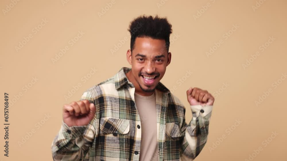 Young happy man of African American ethnicity he wear shirt casual clothes dance waving expressive gesticulating hands fool around have fun feel music rhythm isolated on plain beige brown background Young happy man of African American ethnicity he wear shirt casual clothes dance waving expressive gesticulating hands fool around have fun feel music rhythm isolated on plain beige brown background