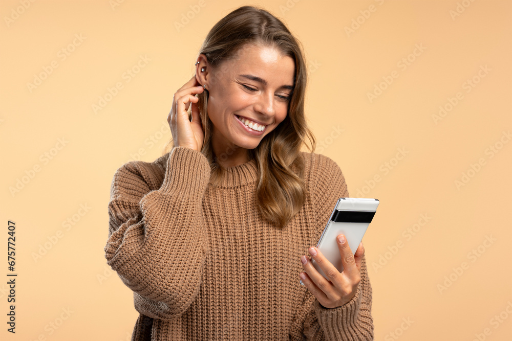 Smiling modern woman wearing stylish brown sweater holding mobile phone, using website, video call Smiling modern woman wearing stylish brown sweater holding mobile phone, using website, video call