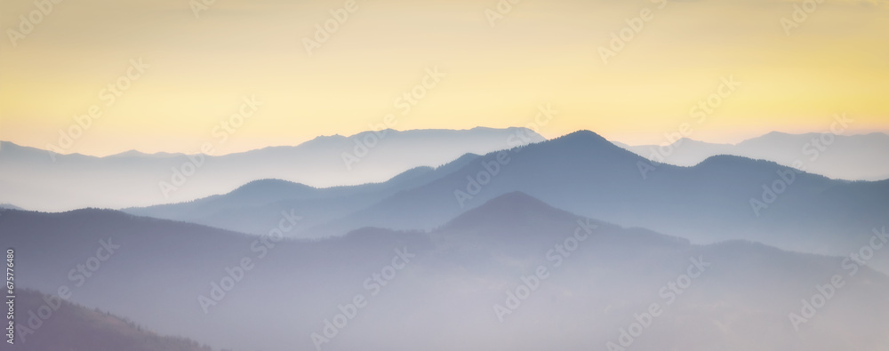 Mountain range with visible silhouettes through the  colorful fog. Photo wallpaper. Natural background. Panorama. Carpathian Mountains, Ukraine