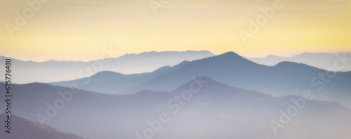 Mountain range with visible silhouettes through the  colorful fog. Photo wallpaper. Natural background. Panorama. Carpathian Mountains, Ukraine © lesia
