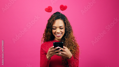 Cute young woman dressed for Valentines Day on dating app cellphone, studio