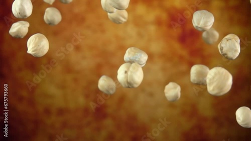 Super close-up of peeled hazelnuts bouncing on a yellow ochre background photo