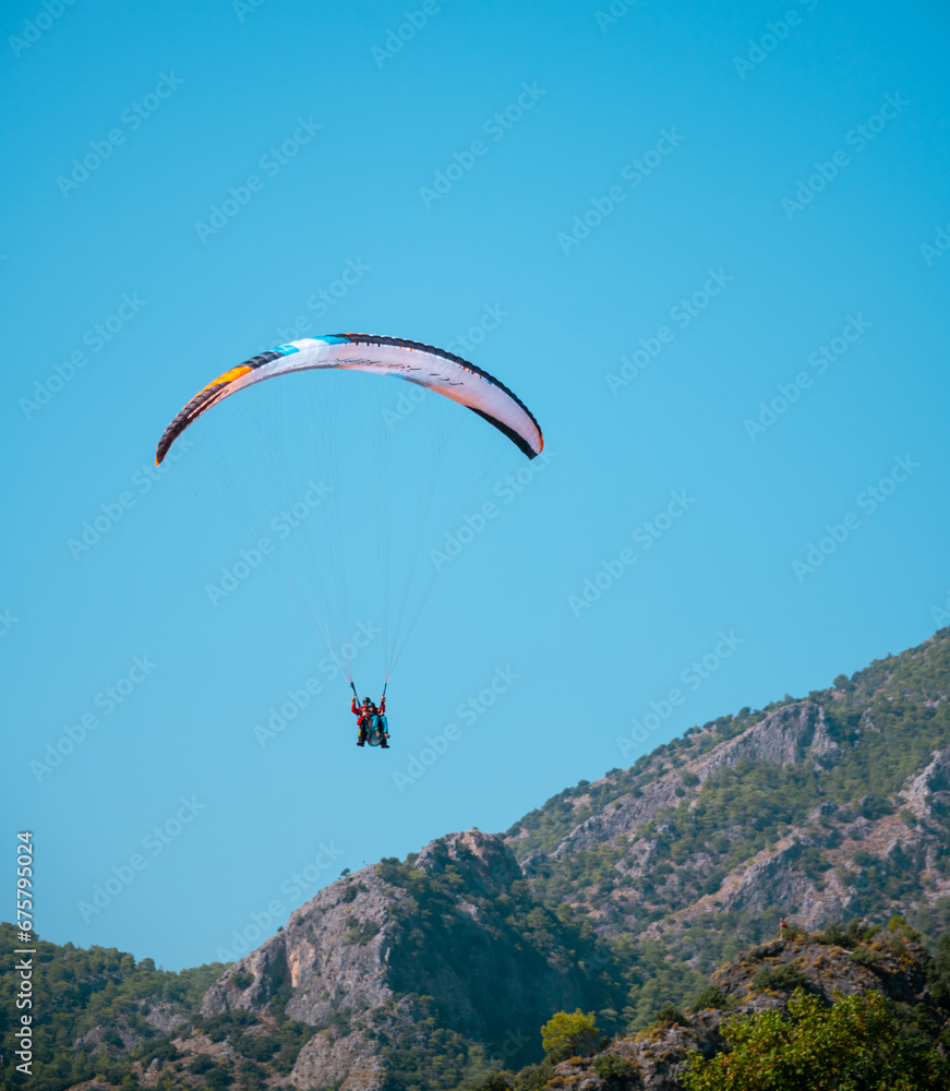 Lonely paraglider flying in the deep blue sky with mountains on the background Lonely paraglider flying in the deep blue sky with mountains on the background