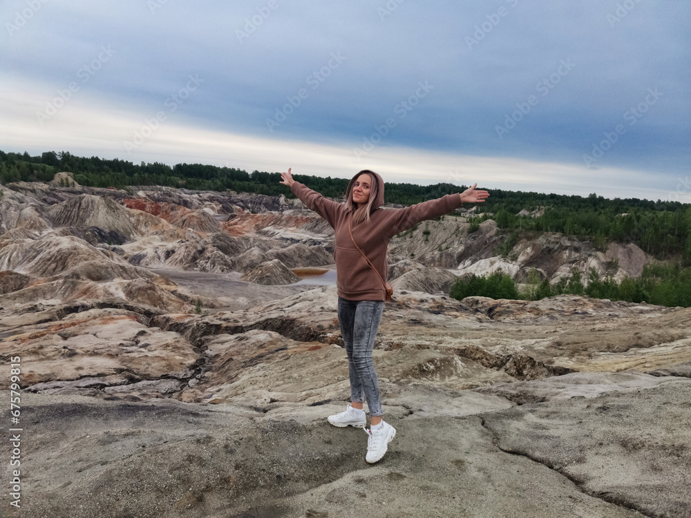 A girl on the background of the Ural Mars. An extraordinarily beautiful summer landscape with red lakes, colorful slopes and forest. Natural landscape, impressive sky. A girl on the background of the Ural Mars. An extraordinarily beautiful summer landscape with red lakes, colorful slopes and forest. Natural landscape, impressive sky.