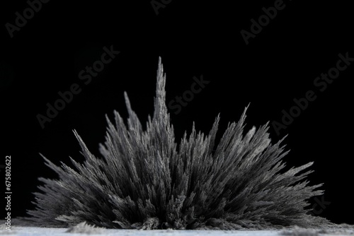 Reaction of iron dust to a magnetic field of a strong neodymium magnet on a black background photo