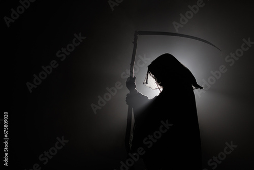 silhouette of death with a scythe. Dark reaper on a black background. Skeleton, skull, silhouette of a man in a black robe depicting death. Halloween characters concept.