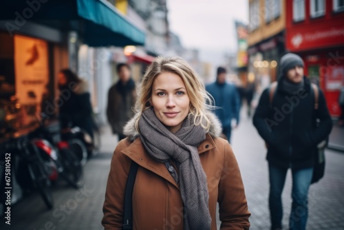 Portrait of a beautiful young blonde woman in a coat and scarf on a city street
