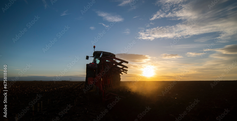 Obraz premium The tractor is working in the field, preparing the soil in the fall after harvesting the corn
