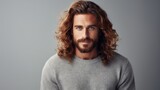 handsome irish red long haired man in grey sweater on grey background