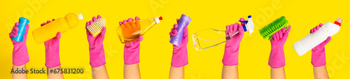 Hand with rubber glove holding cleaning products on a yellow background. banner. Cleaning concept.