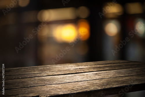 Empty wooden background for your display space. Blurred bokeh background of cafe window reflections of holiday lanterns with empty wooden tabletop for your product