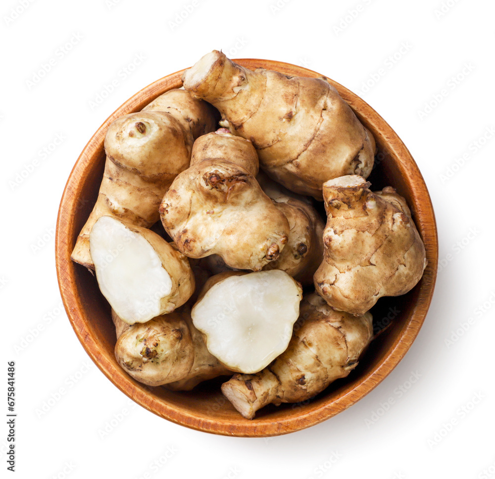 Jerusalem artichoke and half in a wooden plate on a white background. Top view Jerusalem artichoke and half in a wooden plate on a white background. Top view