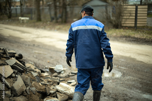 Worker in blue clothes. Road worker removes rocks. photo