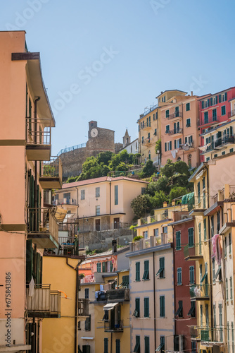 Architecture of street with colorful buildings and tower of castle in background, Riomaggiore ITALY photo