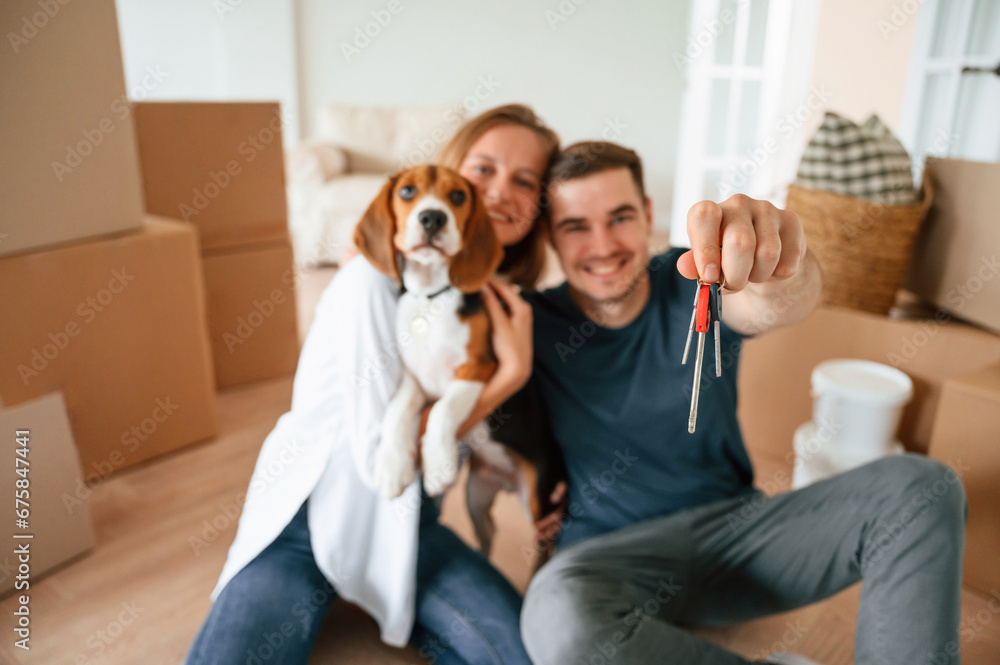Holding keys for new appartment. Young couple with dog are moving to new home Holding keys for new appartment. Young couple with dog are moving to new home