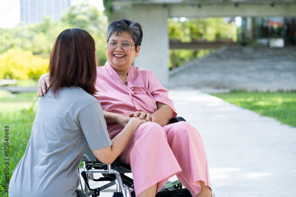 Asian careful caregiver or nurse taking care of the patient in a wheelchair.  Concept of a happy retirement with care from a caregiver and Savings and senior health insurance, encourage the patient