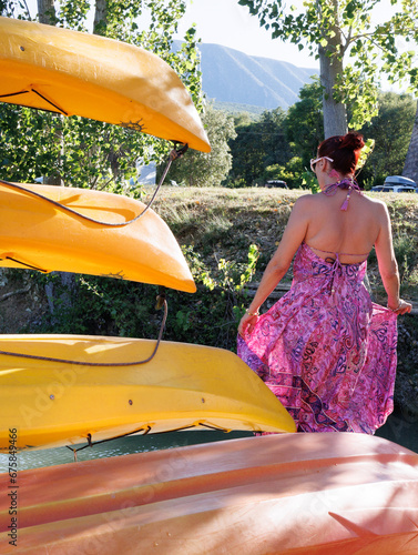 Mujer en verano de espalda mirando el pantano entre kayacs en el embarcadero