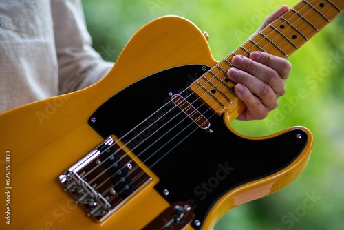 фотографія Closeup shot of a male holding an orange black modern electric guitar