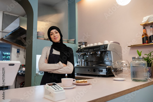 Portrait of young woman in hijab working in cafe