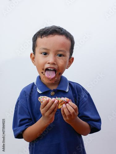 cute little asian boy eating donut isolated on white background