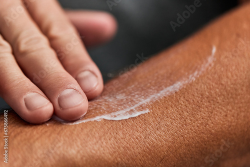 Fotografie A male putting a lotion on his skin, taking care of his skin, rubbing with his fingers