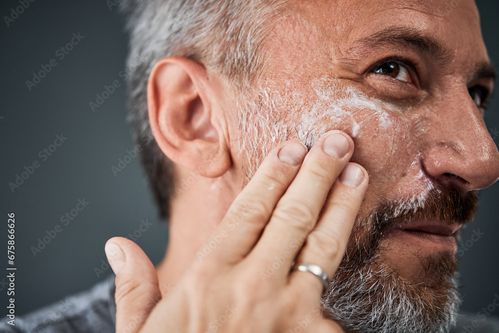Close-up of a mature man, applying a face cream on his cheek, using his fingers. Close-up of a mature man, applying a face cream on his cheek, using his fingers.