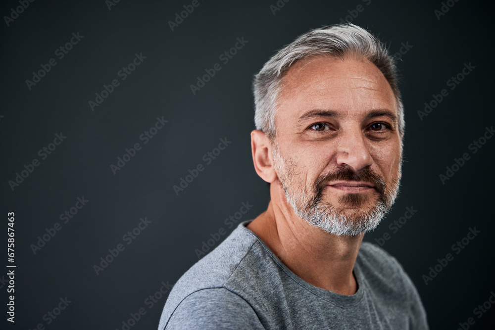 Fototapeta premium Close-up portrait of a senior man, posing on the grey background, looking at the camera.