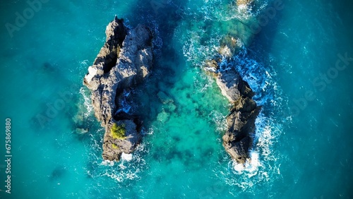 an aerial view of two boats out in the ocean at a rocky cove