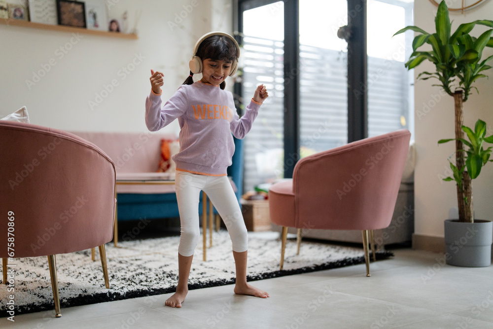 Little girl dancing with headphones in living room Little girl dancing with headphones in living room