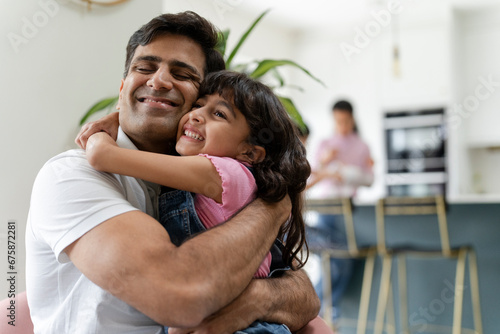 Father hugging daughter at home