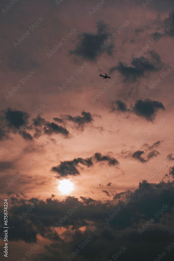 an airplane flying high in the sky at sunset near a mountain