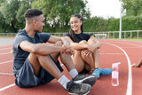 Couple of athletes resting at sports track after training