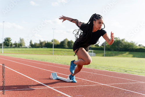 Female athlete sprinting off starting line at stadium © Cultura Creative