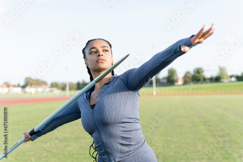 Portrait of female athlete throwing javelin photo