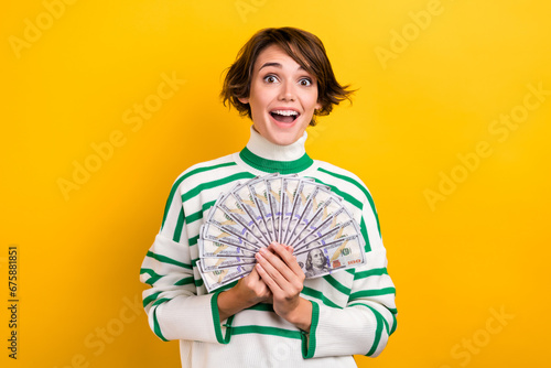 Photo of excited impressed girl dressed striped sweater rising money fan isolated yellow color background