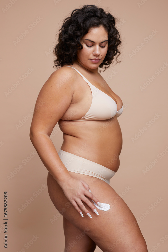 Studio shot of young woman using anti-cellulite cream Studio shot of young woman using anti-cellulite cream