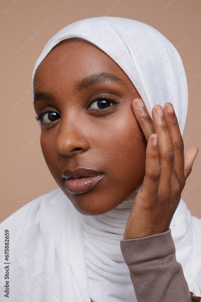 Studio portrait of young woman in white hijab touching face Studio portrait of young woman in white hijab touching face
