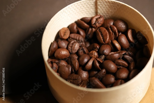 Close up of a beige wicker container filled with coffee beans on a wooden table