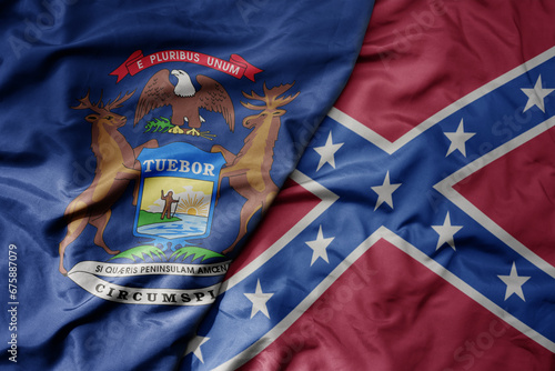 big waving colorful confederate jack flag and flag of michigan state . photo