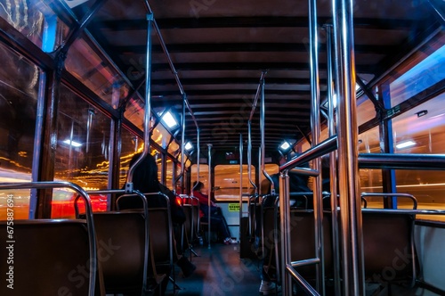 Fotografie Public transport bus with people sitting in it, at night