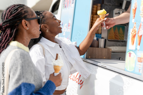 Young female friends buying ice cream in ice cream truck