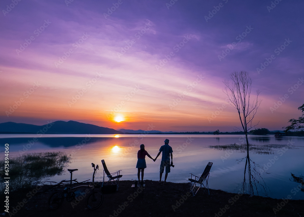 Photo silhouette scene, man, woman, travel couple stand and holding hands watch sunset at last light on New Year's Eve, enjoy relax in vacation. Romantic on holiday at lake in Huai Mai Teng, Thailand