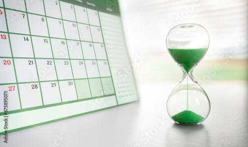 Foto Hourglass and green calendar