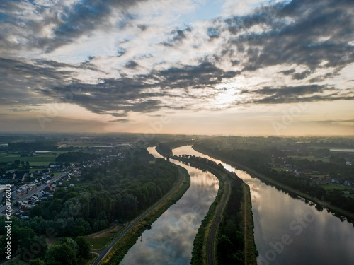 As dawn unfolds, an aerial perspective reveals a breathtaking scene where two waterways, the river and the canal, become mirrors to the heavens. The sunrise spills a spectrum of dramatic colors across © Bjorn B