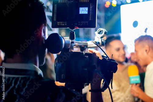 Camera man recording television reporter during interview at live event at night