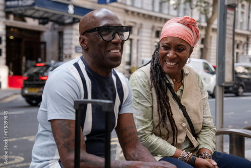 UK, London, Happy mature couple sitting at bus stop